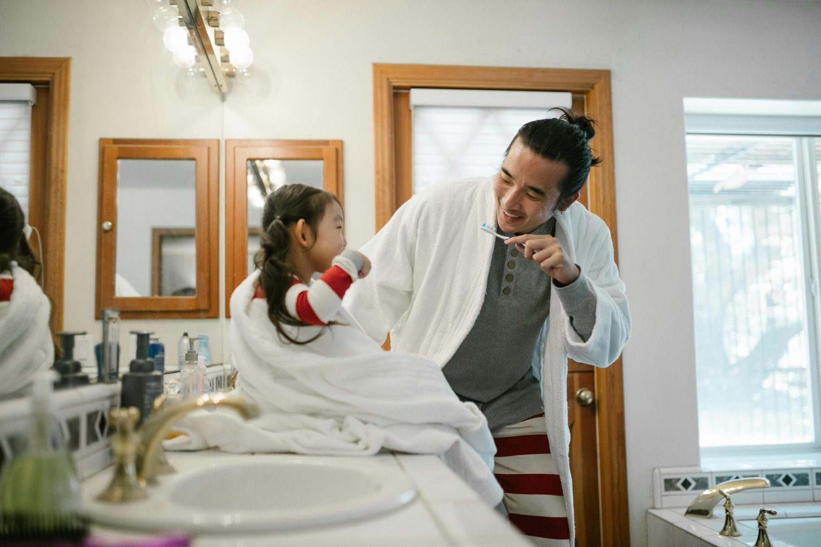 Parent helping a child brush their teeth in the morning, showing a simple daily routine that supports healthy daily habits at home.